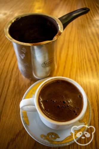 A small Arabic pitcher and cup and saucer with Arabic coffee.