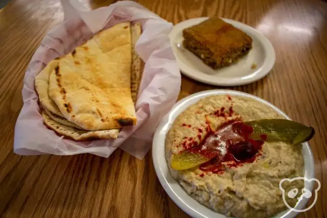 Middle Eastern food, including a basket of pita, kibbi meatloaf, and baba ganooj roasted eggplant dip.