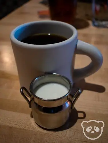 Coffee in mug with small cup of milk. 