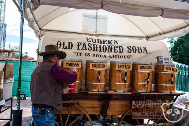 Man next to soda taps in the shape of barrels.