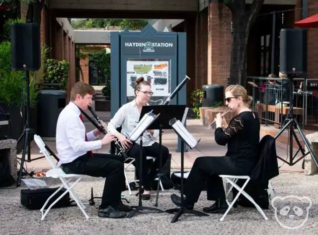 A man and two women sitting and playing musical instruments.