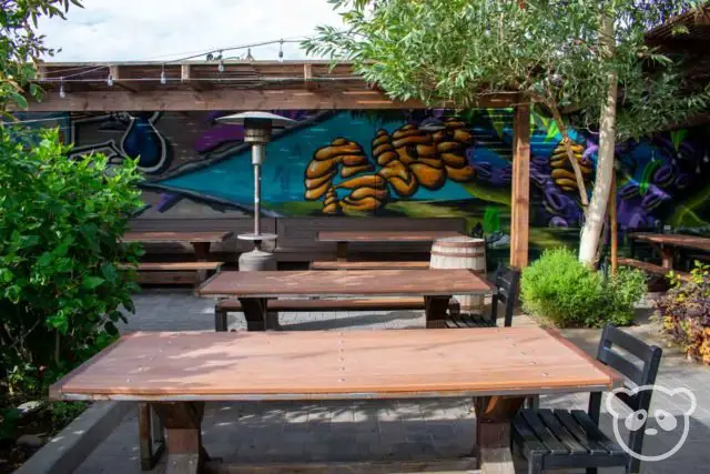 Tables and chairs in the outdoor seating area along with a painted mural in the background. 