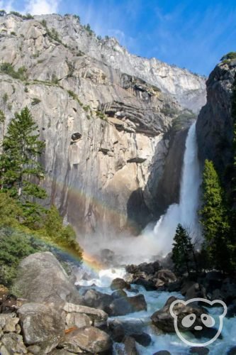 waterfall plunging from granite rock with double rainbow