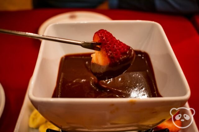 Strawberry dipped into chocolate with a fondue fork. 
