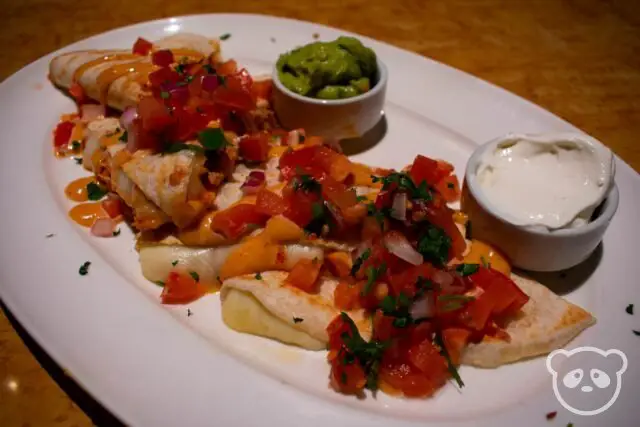 Plate of quesadillas with salsa, guacamole, and sour cream. 