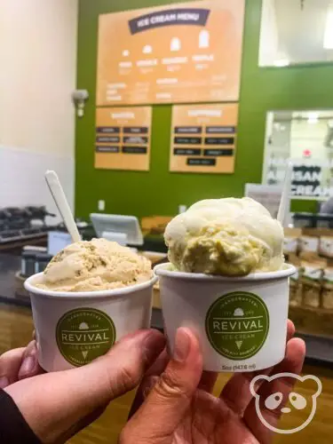 Two cups of ice cream with hands holding them.