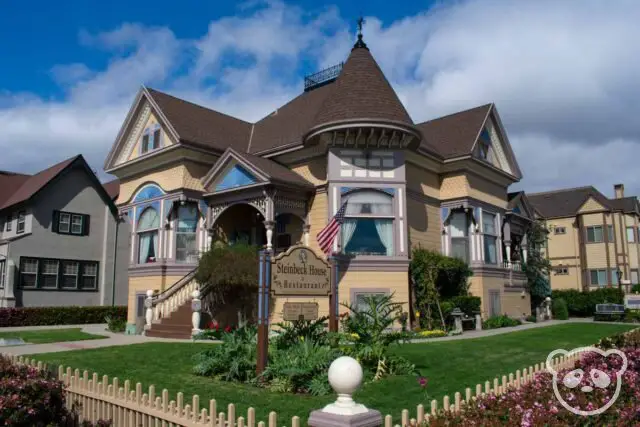 Victorian house with landscaped grass and white picket fence around it