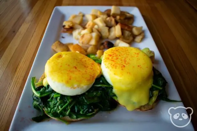 Eggs benedict with spinach and a side of potatoes.