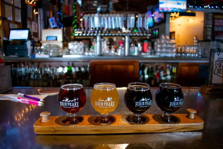 The Best Bars, Breweries, & Distilleries in Tempe, Arizona Beer flight of four beers with the bar and taps in the background.