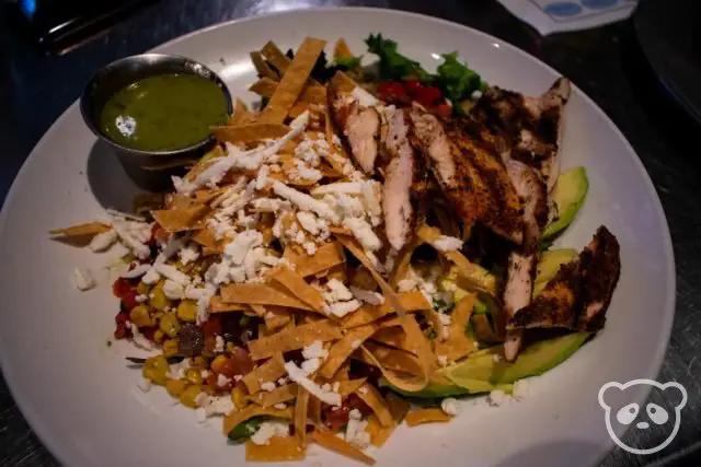 Plate of salad with chicken and tortilla chip strips. 