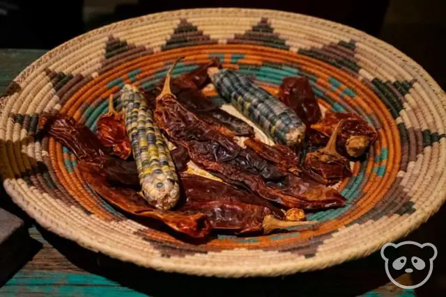 Dried multi-colored corn and chili peppers in a basket.