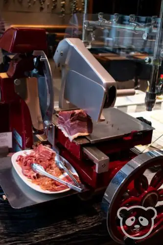 Prosciutto slicer with a plate of prosciutto next to it. 