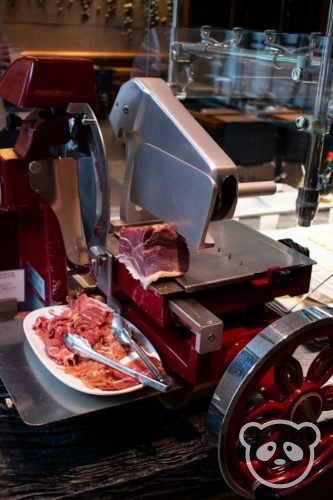 Prosciutto slicer with a plate of prosciutto next to it.
