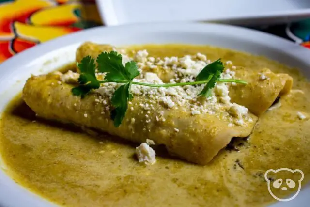 Two enchiladas on a plate covered with sauce.