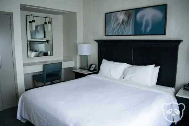 hotel bedroom with double bed, desk, chair, and end tables with lamp