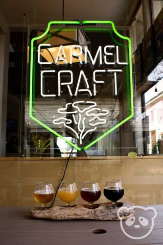 a flight of beers in front of a carmel craft neon sign