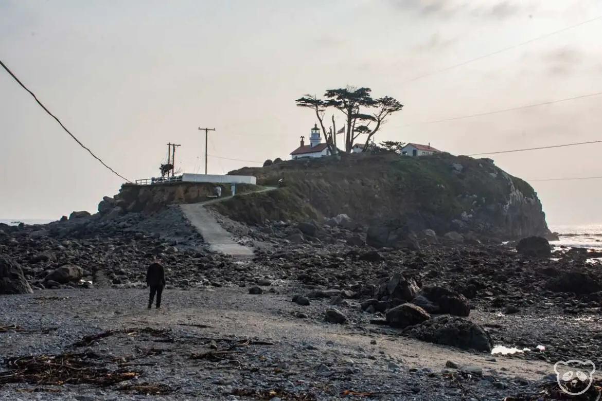 Battery Point during low tide when the pathway to the island is accessible with a man for scale.